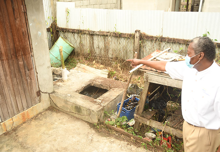 A relative pointing to the septic tank where the body was discovered 
(Adrian Narine photo)