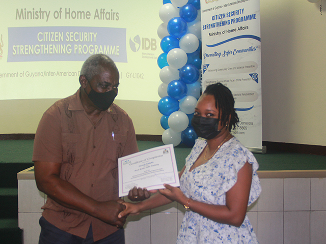 One of the recipients receiving her certificate from Home Affairs Minister, Robeson Benn