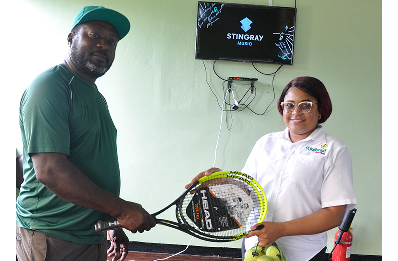 Wendell James hands over racquets and balls to  Kwakwani management.