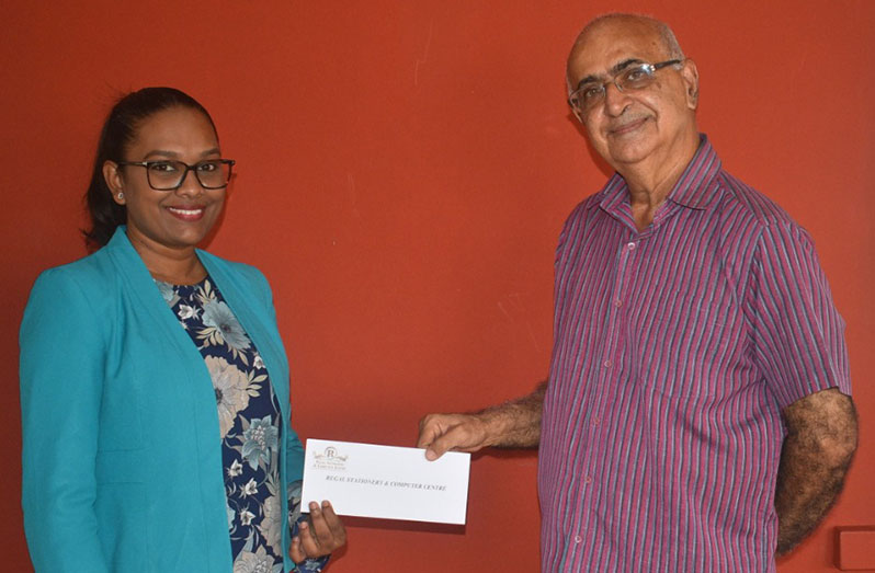 Manager of Regal Stationery and Computer Centrem Telesha Ousman (left), hands over the donation to Rajnarine Singh of the Guyana Hindu Dharmic Sabha.
