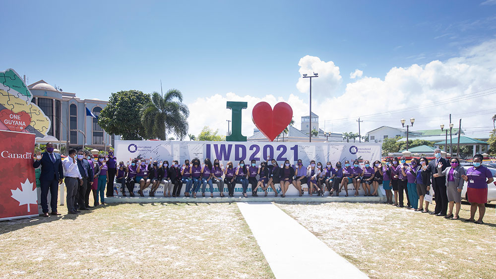 Staff of the GBTI and other officials at the ‘I Love Guyana’ sign to mark International Women’s Day