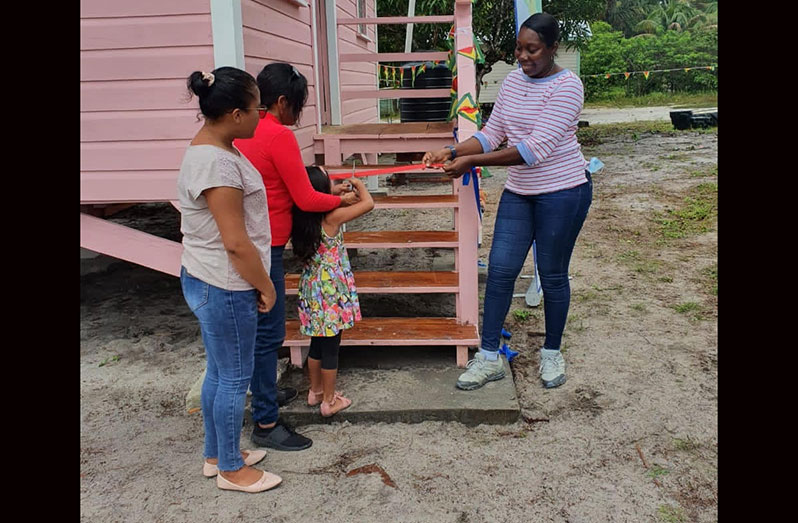 Senior Project Manager at Food for the Poor Guyana, Andrea Benjamin (right), facilitates the ceremonial ribbon-cutting exercise as part of the official handing over of one of the houses to a beneficiary