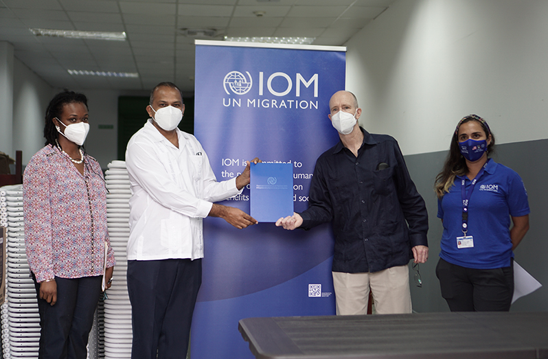 Chief of Mission of IOM, Robert Natiello (second right), handing over a copy of the donation agreement to Minister of Health, Dr Frank Anthony (second left)