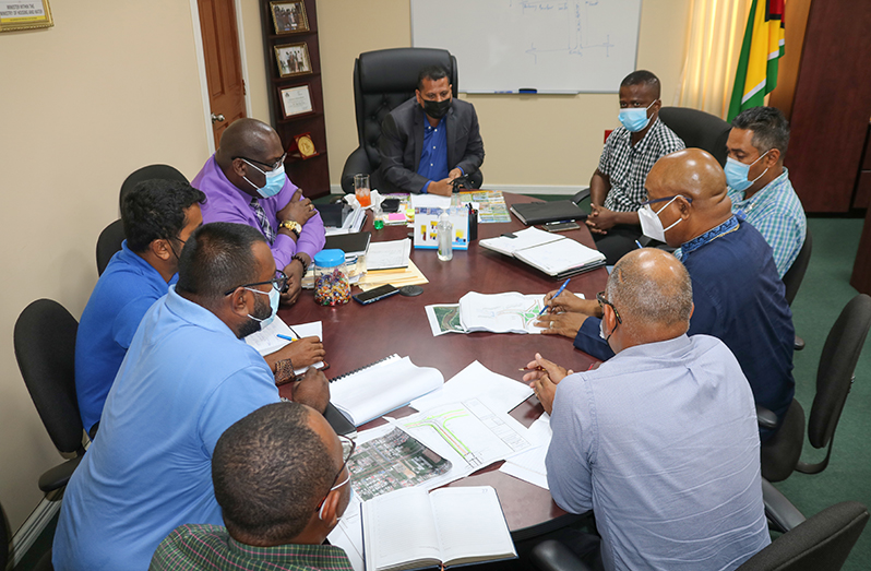 Housing Minister and Public Works Minister along with technical staff examining a map of the road expansion project