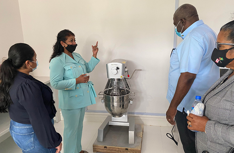 Guyana Foundation founder, Supriya Singh-Bodden, using a modern piece of mixing equipment to explain the baking process to Prime Minister Mark Phillips, First Lady Arya Ali and Region Two Chairperson Vilma De Silva