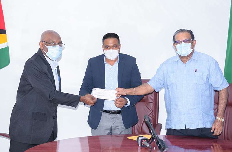 Councillor Oscar Clarke, left, receiving the $30 million cheque from Minister of Local Government and Regional Development, Nigel Dharamlall, centre,   and Minister within the Ministry of Local Government and Regional Development, Anand Persaud