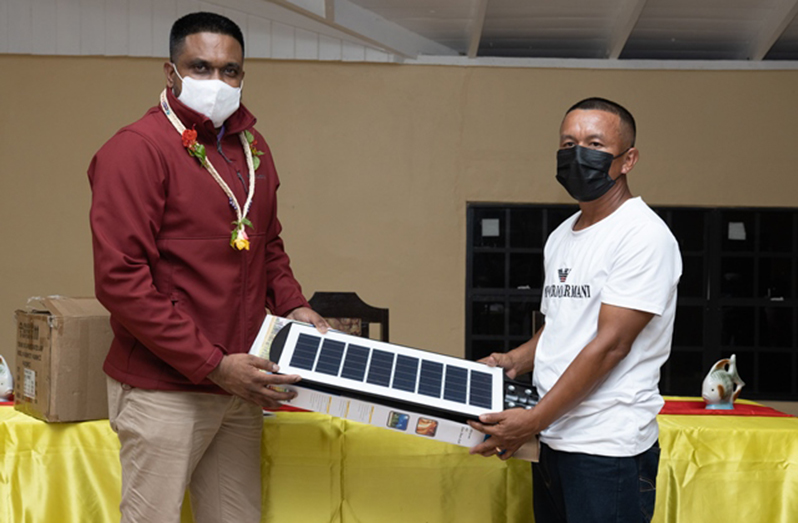 Minister of Local Government and Regional Development, Nigel Dharamlall, hands over solar-powered lights to Toshao of Waramuri, Vivian Edwards