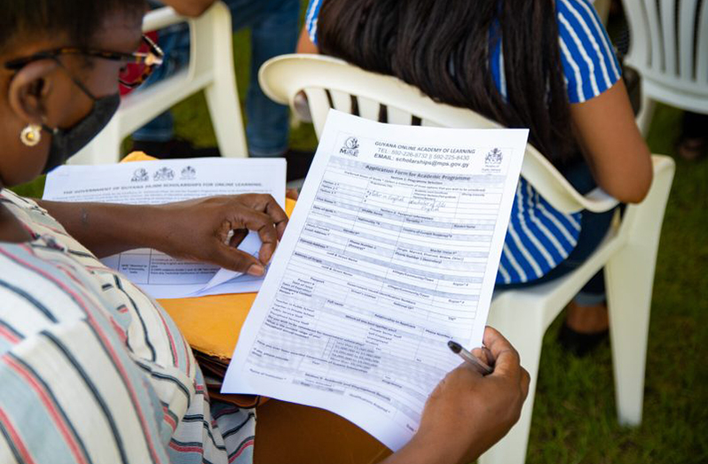 Citizen examining a GOAL scholarship form during the programme launch at the synthetic track and field facility, Region Three