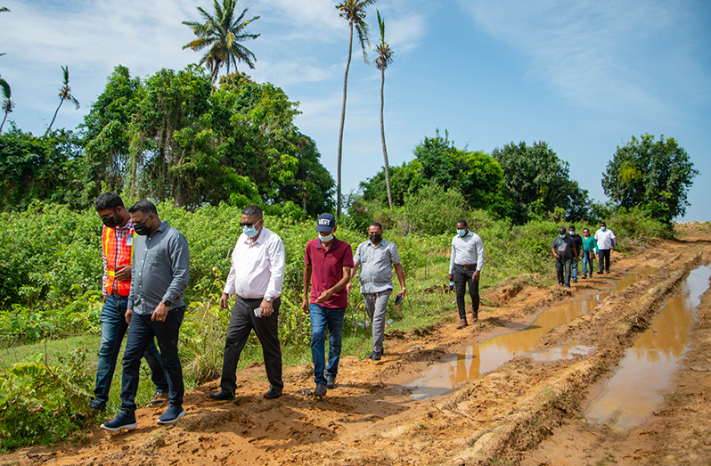Minister Indar, along with members of the NDC, walking along a section of the dam that was destroyed by BK machines (DPI photo)