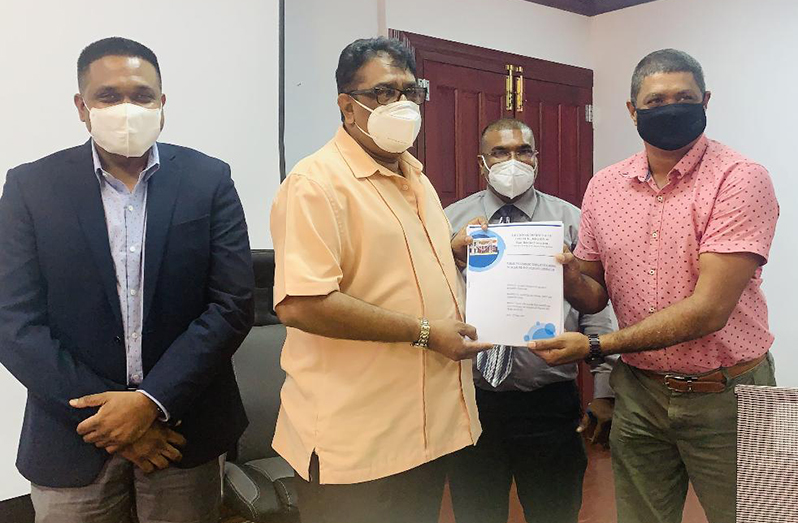 Imran Shaffeeullah of Shaffeeullah Sawmill receiving his contract from Regional Chairman, David Armogan in the presence of Minister of Local Government and Regional Development, Nigel Dharamlall and Regional Executive Officer, Narendra Persaud 