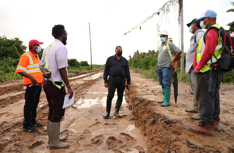Minister Croal interacts with representatives of the contracting service constructing a new access road at Experiment, Region Five
