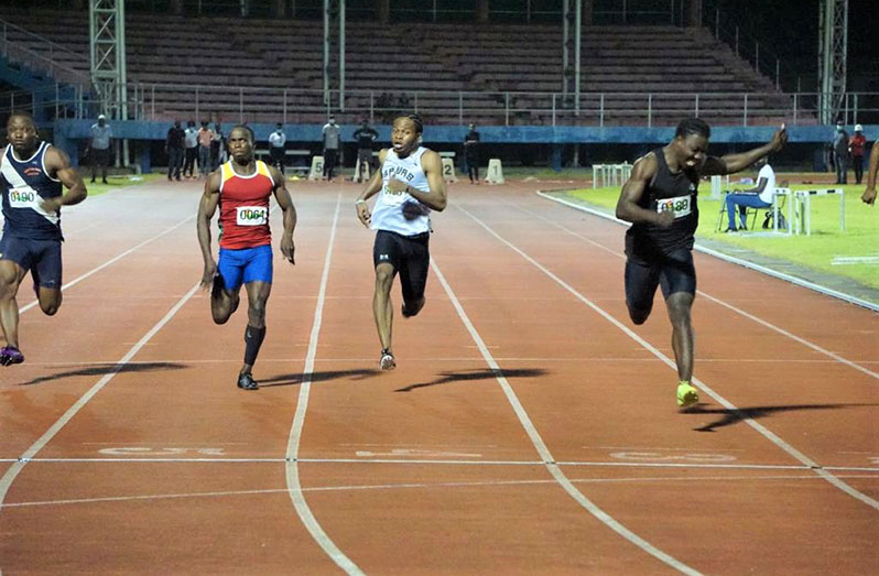 Emanuel Archibald (far right) wins the 100m on Friday evening at the National Track and Field Facility.