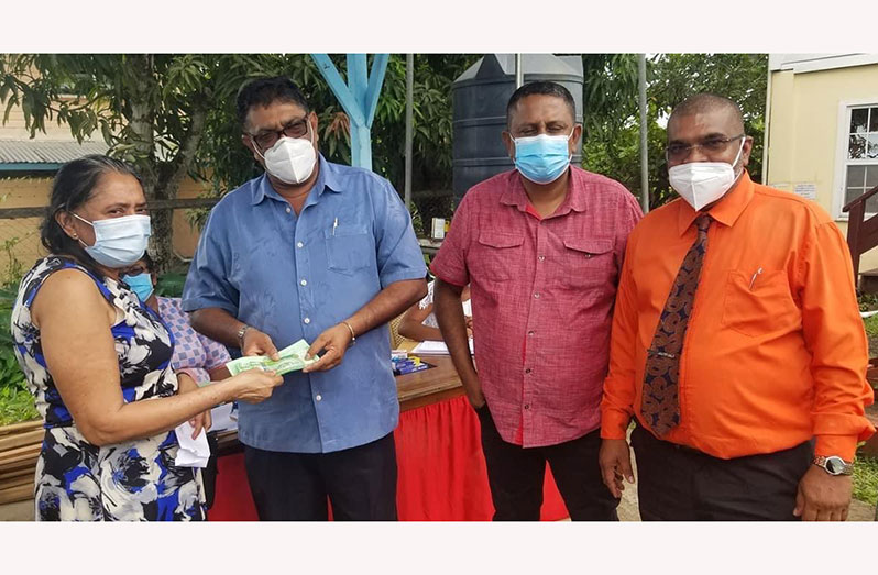 Regional Chairman, David Armogan hands over the grant to a resident of Canje. Also in photo are Regional Vice-Chairman, Zamal Hussain, and Regional Executive Officer, Narindra Persaud 