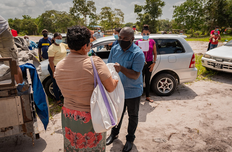 Minister in the Office of the Prime Minister with responsibility for Public Affairs, Hon. Kwame McCoy hands over a food hamper to a resident of Tigerbone/Banakari