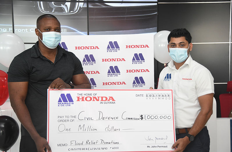 CDC Deputy Director General, Major Loring Benons (left), receiving the $1M cheque from Sales Executive of Marics and Company Limited, Khemraj Jaikaran
