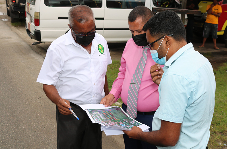Minister of Housing and Water Collin Croal, (centre),  flanked by head of NAREI Jagnarine Singh and an engineer attached to the CH&PA, examine the site plan for the housing development and new access road