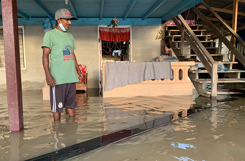 Deonarine Sohan stands in his flooded yard