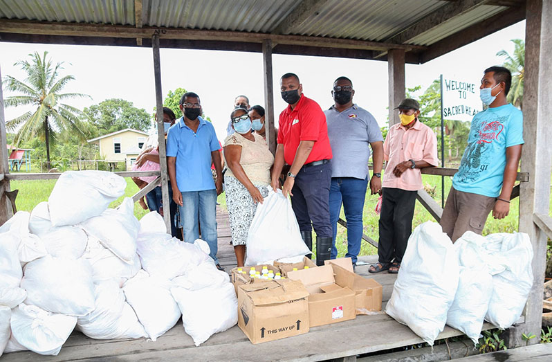 Minister of Housing and Water, Collin Croal and other officials distribute the hampers to residents of Sacred Heart