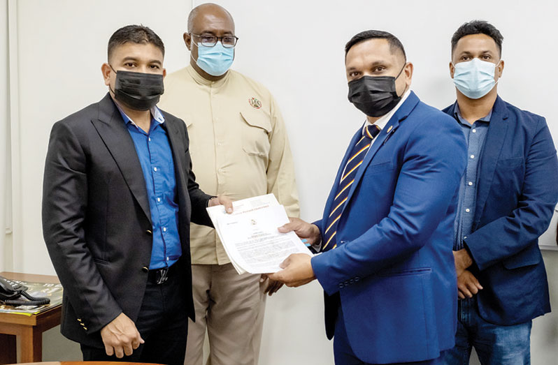 Azruddin Mohamed collecting the quarry licence from Natural Resources Minister, Vickram Bharrat while GGMC Commissioner, Newell Dennison (second left) looks on