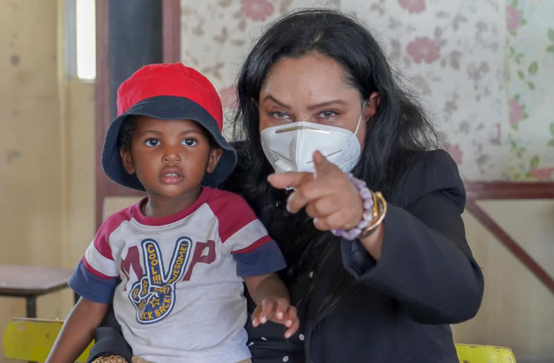 Minister of Human Services and Social Security, Dr Vindhya Persaud, with a child during an outreach