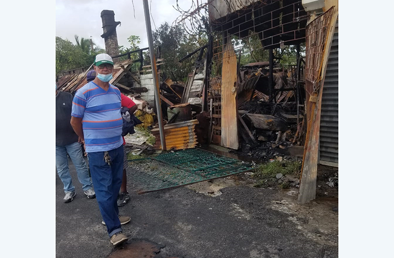 Herman Faria stands next to what is left of his building