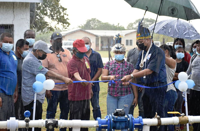 Minister of Housing and Water, Collin Croal, braving the rains with Regional Chairman of Region Nine, Brian Allicock and other officials at the ribbon-cutting ceremony of the newly commissioned water distribution system