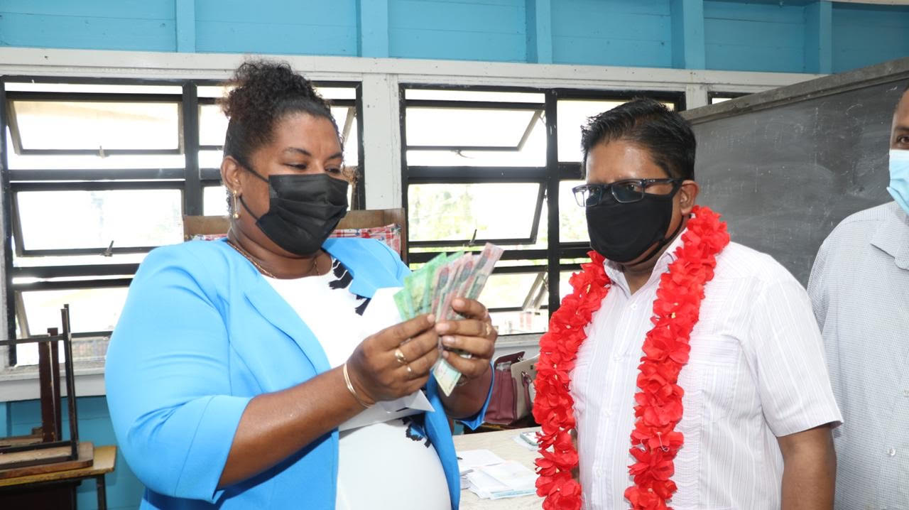 Headteacher of Betsy Ground Primary School, Debra Ward, counts her cash which will go towards the purchase of a computer for her son who is preparing to write the NGSA. Looking on is Senior Minister with Responsibility for Finance in the Office of the President, Dr.Ashni Singh