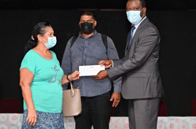 Minister of Foreign Affairs and International Co-operation, Hugh Todd, hands a beneficiary her flood-relief cheque (DPI photo)