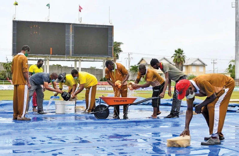The ground staff at Sabina Park mopping up water from the covers ( AFP/Getty Images)