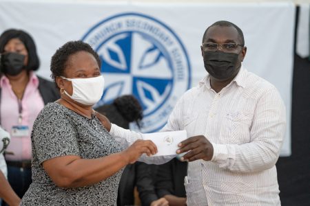 Minister within the Office of the Prime Minister with responsibility for Public Affairs, Kwame McCoy, hands over a cash grant to a parent (DPI photo)