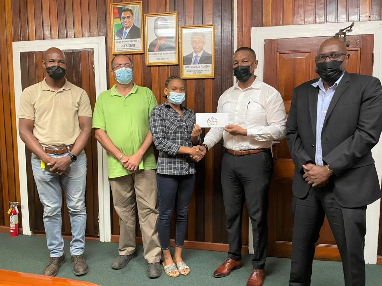 Chairman of the NSC, Kashif Muhammad, makes a presentation to Aleka Persaud in the Boardroom of the National Sports Commission, in the presence of GASA president Dwayne Scott, coach Sean Baksh and Director of Sport, Steve Ninvalle.