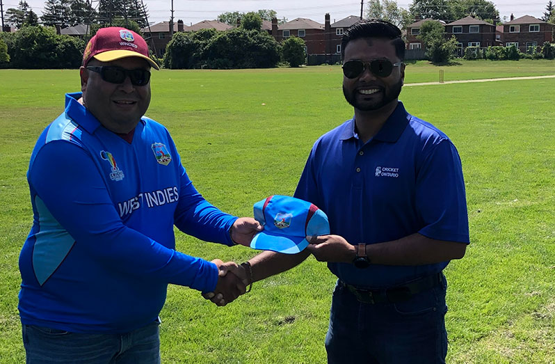 CWIMA Over-50s manager,  Raj Singh (left) presents a team cap to SCA President, Shiv Persaud.