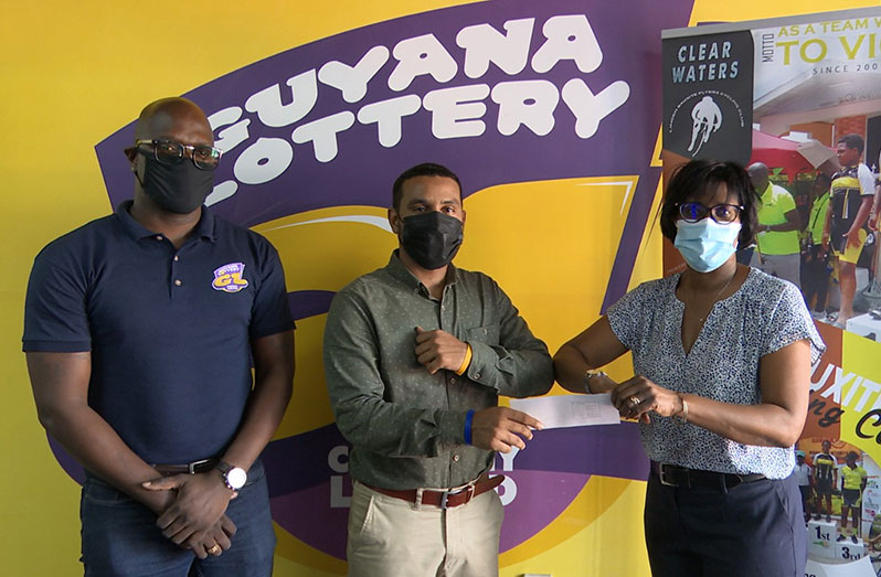 Guyana Lottery Company’s General Manager Tracey Lewis makes a presentation to Linden Bauxite Flyers Cycle Club’s Jeffrey Yearwood. Also in photo is the company’s Brand Ambassador, Rawle Toney.