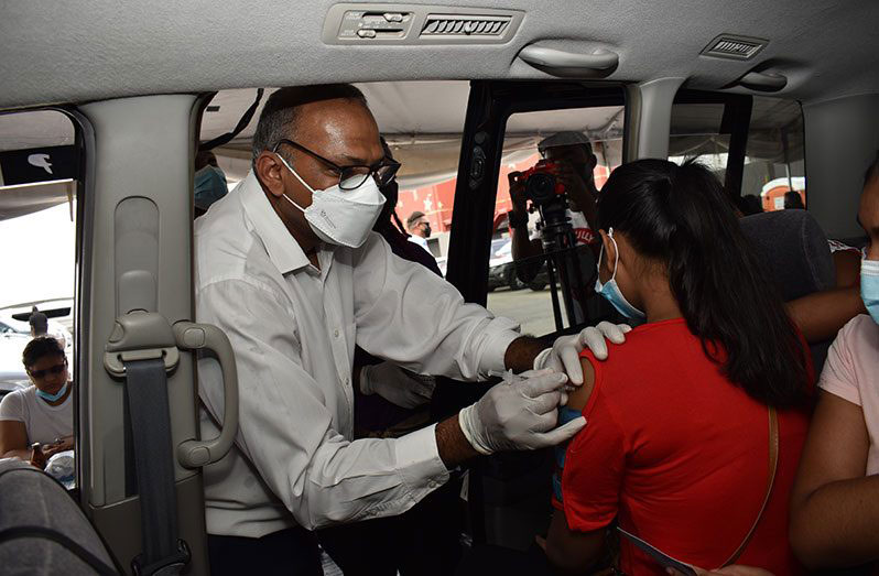 Health Minister, Dr. Frank Anthony, administering a dose of the Pfizer-BioNTech COVID-19 vaccine to a child during the COVID-19 drive through at the MovieTowne parking lot, East Coast Demerara, last Sunday (Elvin Croker photo)
