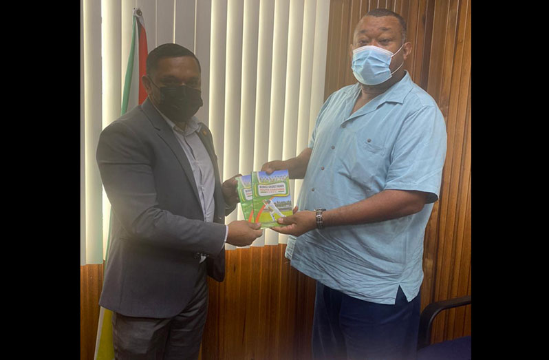 BCB president, Hilbert Foster, hands over copies of the board historic coaching manual to BCB Patron, Minister Vickram Bharrat.