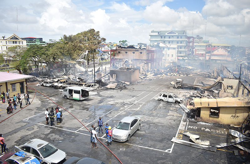 A fire of unknown origin completely gutted several buildings inside the Brickdam Police Station compound on Saturday, destroying years of police records and millions of dollars worth of vehicles. A ‘595-photography’ drone photo shows the fire ravaging the wooden structures, while photographer Elvin Croker captured the aftermath of the devastation