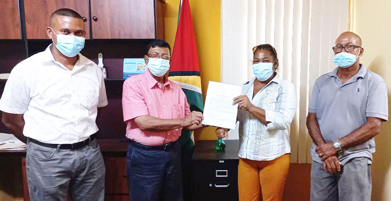 GWI's CEO, Shaik Baksh, hands over the contract to River's View Toshao, Melena Pollard