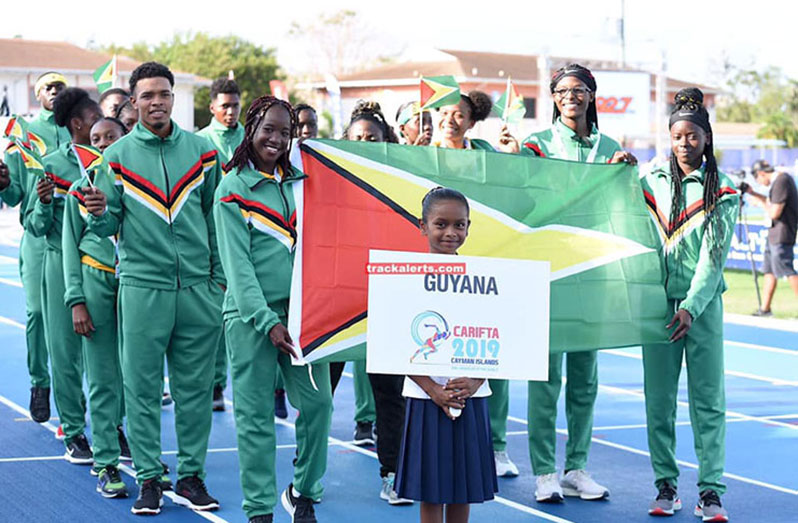 FLASHBACK! Chantoba Bright and Claudrice McKoy carrying the Golden Arrowhead and leading some members of Guyana’s contingent of athletes at the opening of the 48th CARIFTA Games in the Cayman Islands. (Track Alerts photo)