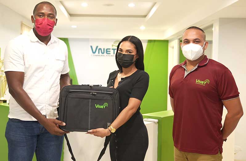 Coach Ryan Hercules (far left) collects his laptop from Sales Representative Whitney Brock in the presence of V-Net’s CEO Safraz Sheriffuden.