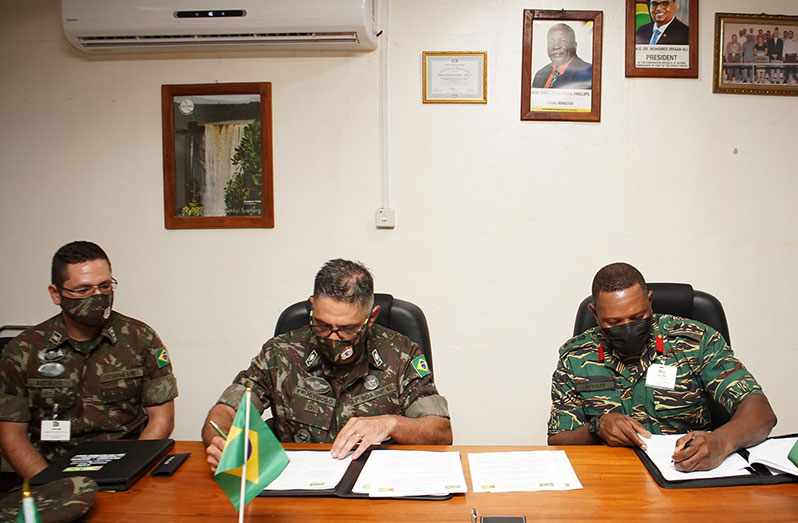 Brigadier-General, Adriano Fructuoso and Colonel Trevor Bowman affix their signatures to the final minutes and new understandings at the conclusion of the meeting on Thursday
