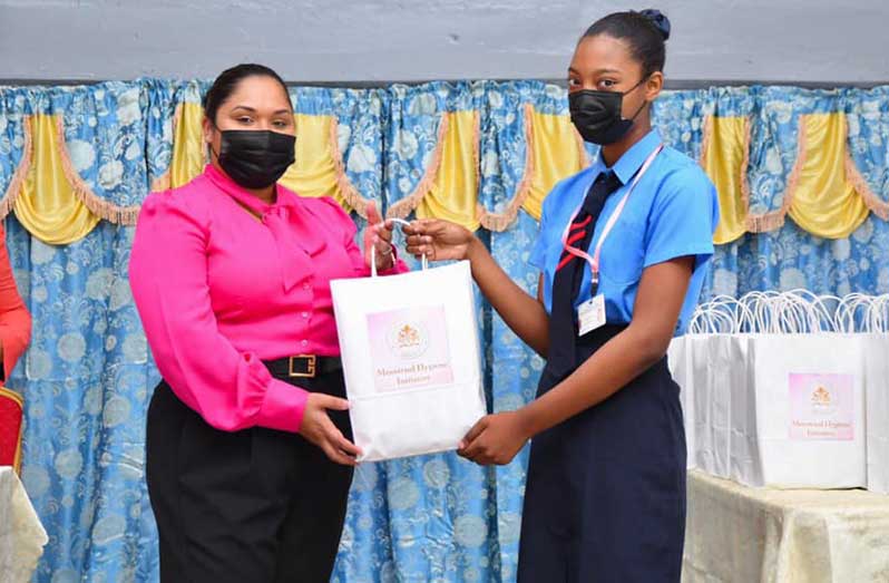 First Lady Arya Ali handing over a supply of sanitary pads to a student