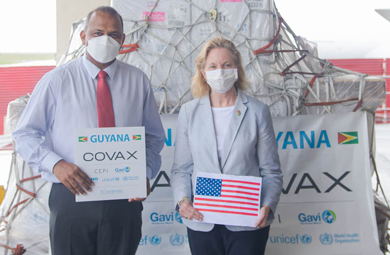 Health Minister, Dr Frank Anthony, and US Ambassador to Guyana, Sarah-Ann Lynch stand behind the cargo of Pfizer vaccine received from the US on Friday (US Embassy photograph)