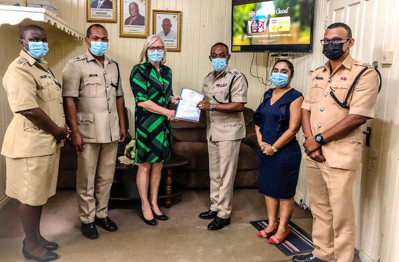 Director of Nations University Pamela O’Toole and Commissioner of Police (ag), Clifton Hicken, in the presence of others, display the signed agreement