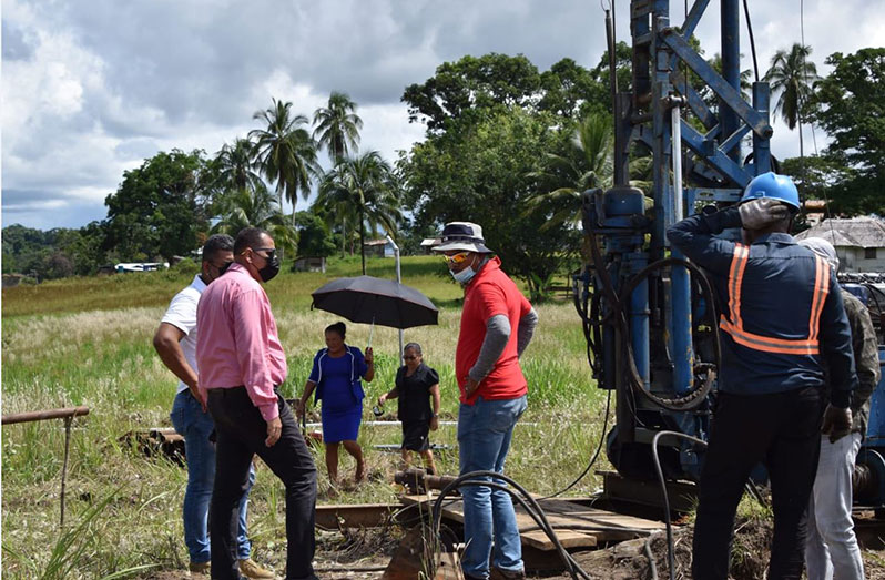 Minister of Housing and Water Collin Croal watches on as workers drill the water well at Central Jawalla