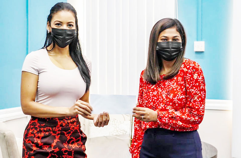 E-Networks Marketing Co-ordinator, Ashley John (left) hands over the cheque to Permanent Secretary of the Ministry of Human Services and Social Protection, Shannielle Hoosein-Outar