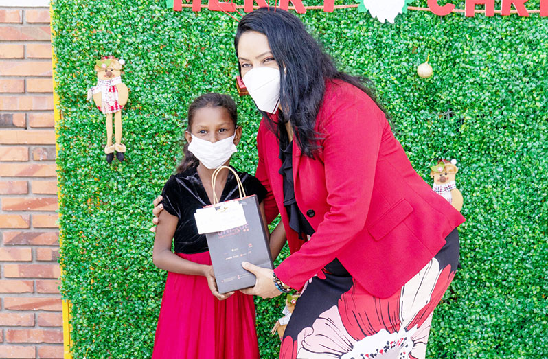 Minister of Human Services and Social Security, Vindhya Persaud, handing over gifts and goodies to this little one