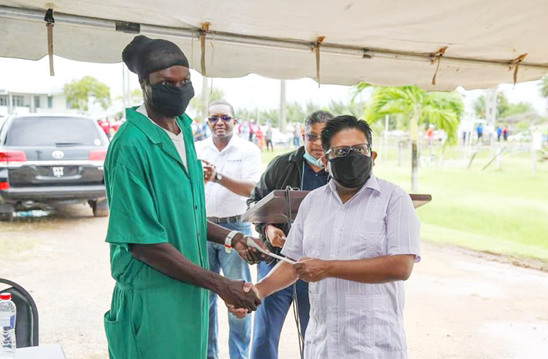 A sugar worker receiving his cheque from Senior Minister in the Office of the President with responsibility for Finance, Dr. Ashni Singh at Enmore, East Coast Demerara