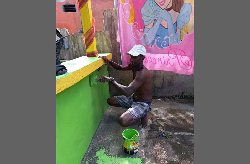 Hussein Bacchus paints his house. This project was funded with part of his cash grant
