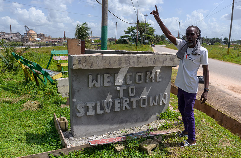 Vice Chairman of the Silvertown Fiesta Support Group posing at the village signage (Delano Williams photos)