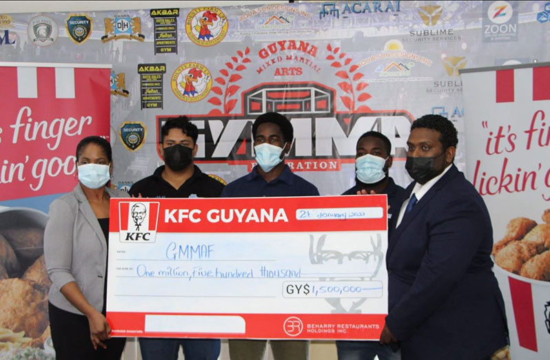 Beharry Restaurant Holdings’ Marketing Officer, Pamela Manasseh, presents her company’s cheque to GYMMA Sherwin Sandy. Also present are several fighters of the GYMMA’s National team